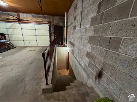 Concrete block walls with a concrete floor and a metal handrail alongside concrete steps