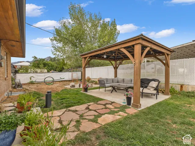 Expansive backyard featuring a stone patio, wooden gazebo structure, and a flagstone pathway