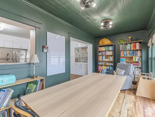 Recessed ceiling with wood-finish paneling, two ceiling-mounted light fixtures, built-in shelving, and wood-finish flooring