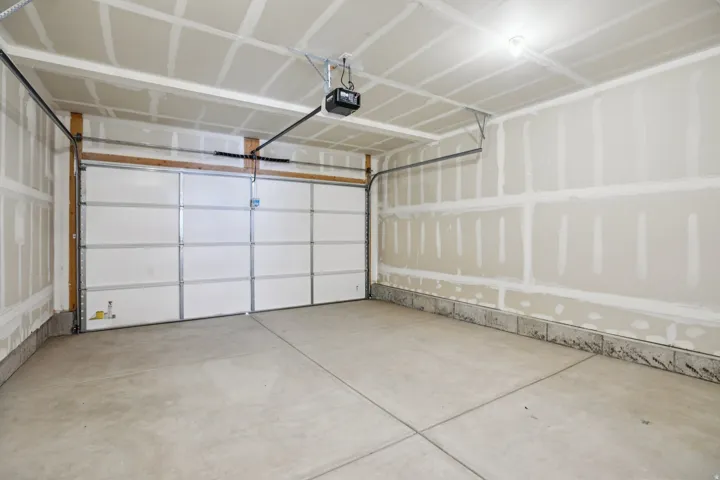 Attached garage with concrete flooring, overhead lighting, and an automatic garage door opener