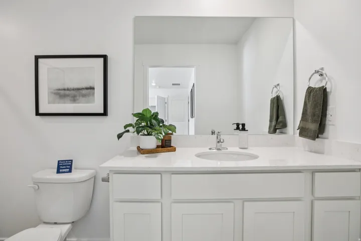 Vanity with an integrated sink, polished chrome faucet, white cabinetry, and a large wall-mounted mirror