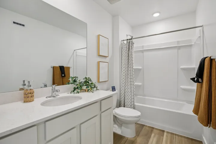 Spa-inspired bathroom featuring a white vanity with dual-sink configuration and ample countertop storage, paired with a white subway tile surround and frameless glass shower enclosure