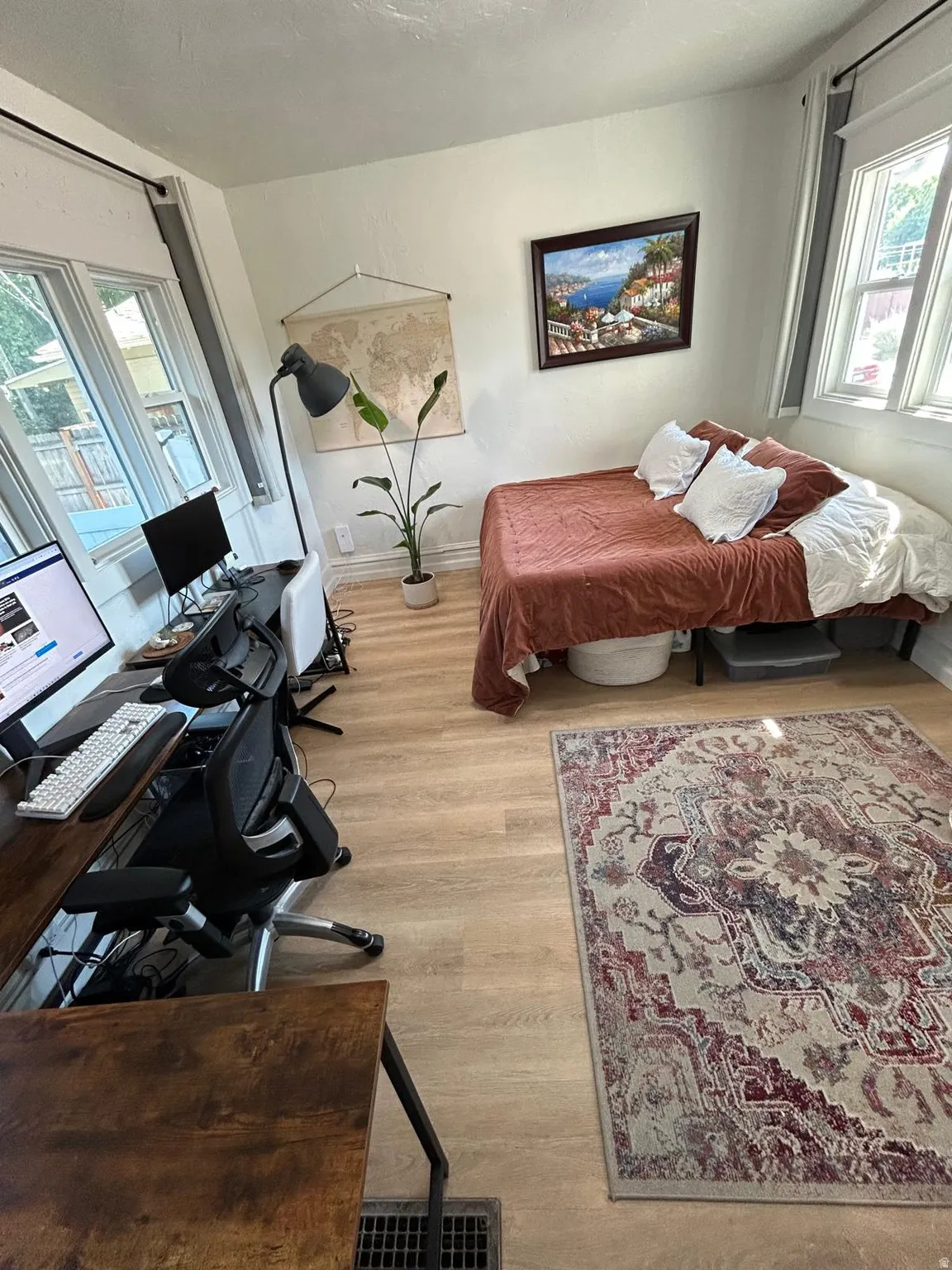 Light-toned wood-finish flooring, multiple windows with natural light, and white wall finishes