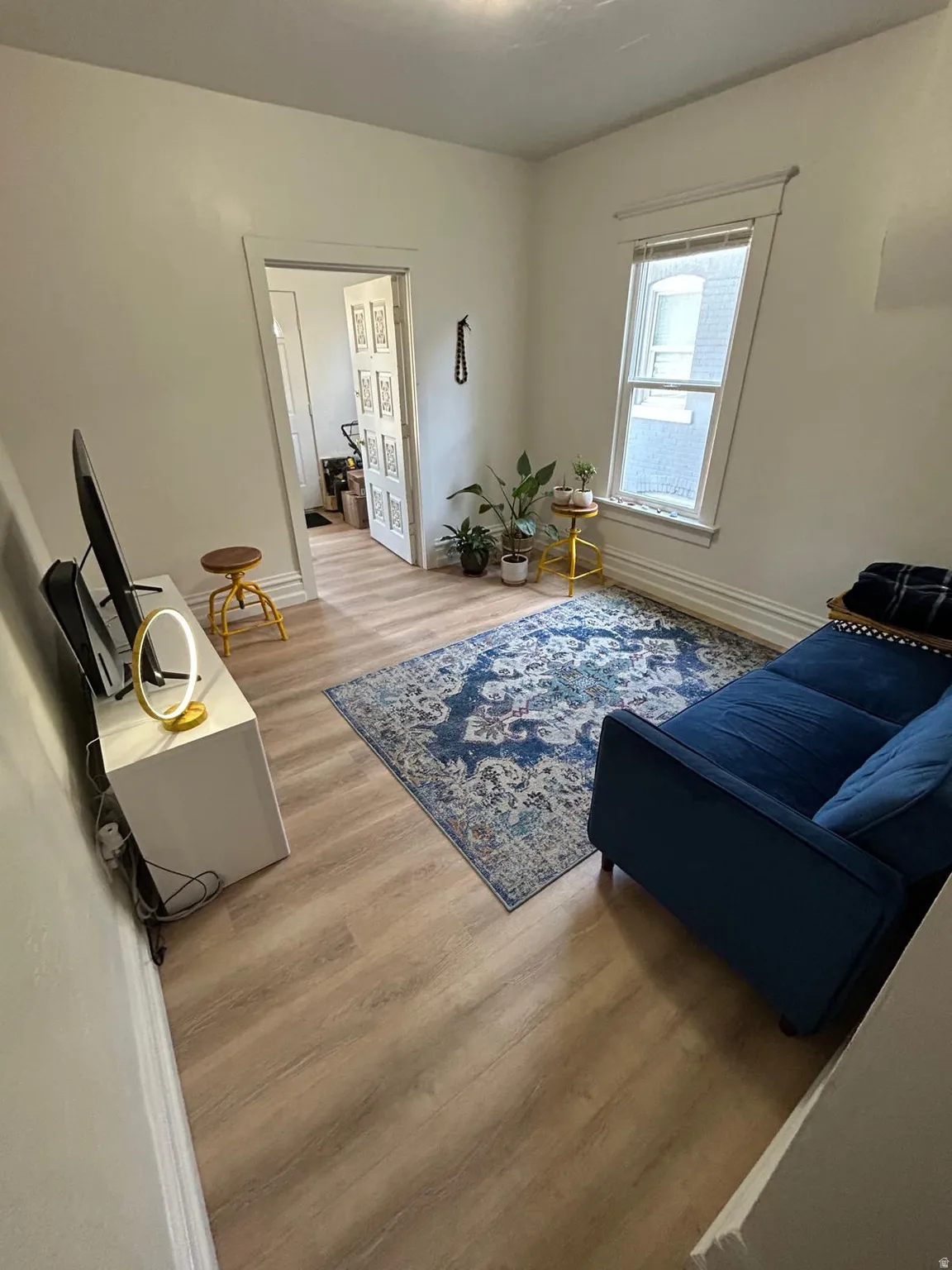 Light wood-finish flooring, white walls, and a window with white trim