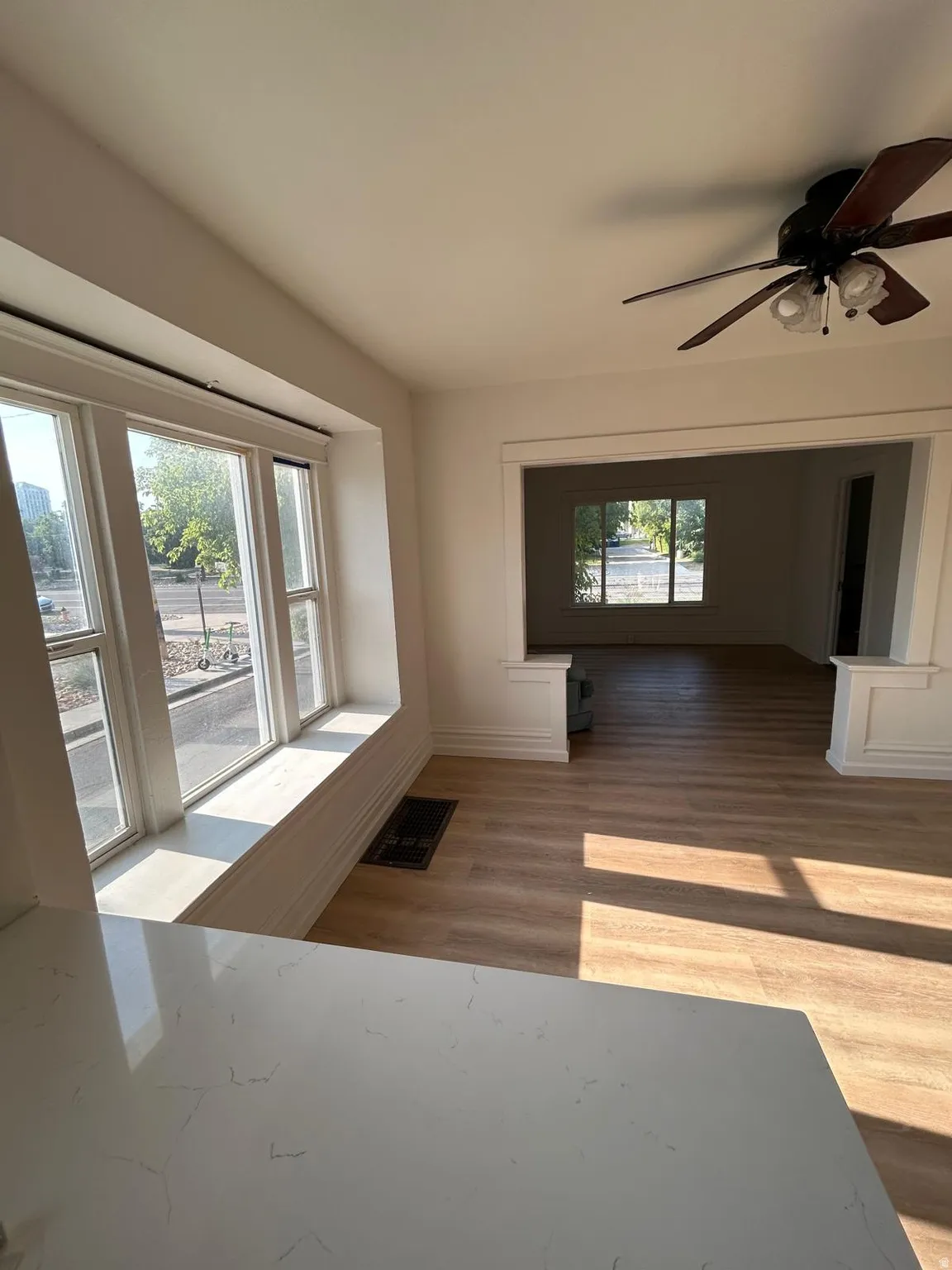 Wood-finish flooring, white walls, and a ceiling fan
