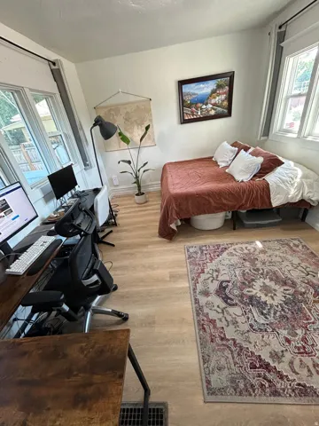 Light-toned wood-finish flooring, multiple windows with natural light, and white wall finishes