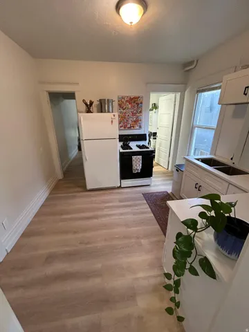 Kitchen featuring wood-finish flooring, white cabinetry, a double basin sink, and a four-burner stove