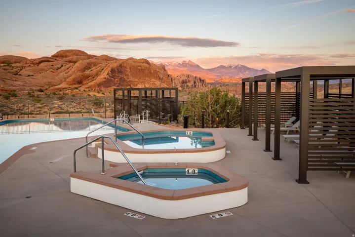 Outdoor aquatic area featuring two hot tubs with integrated steps and handrails