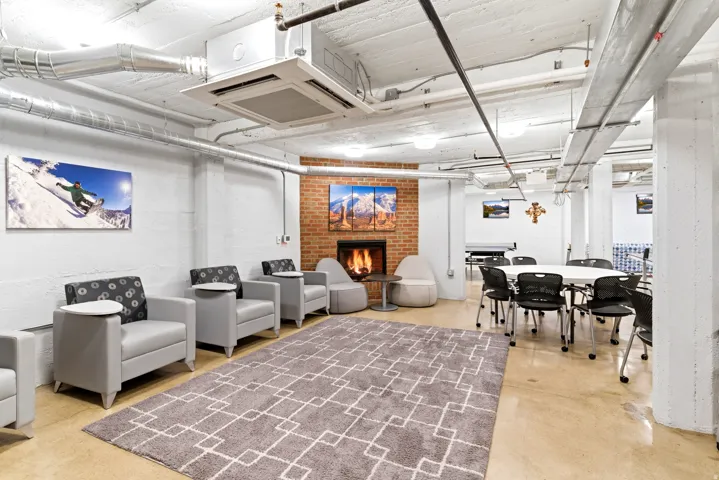 Exposed brick fireplace, concrete flooring, exposed ceiling ductwork, recessed lighting, and white painted walls