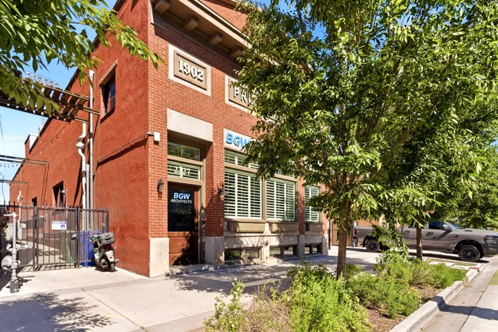 Brick and stucco exterior with prominent 1902 facade detail, ground-level entry, and street-facing window with shutters