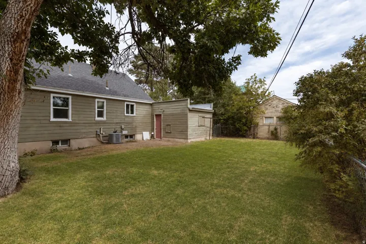 Expansive lawn area, mature trees, single-story detached structure, additional utility building, and a fenced perimeter
