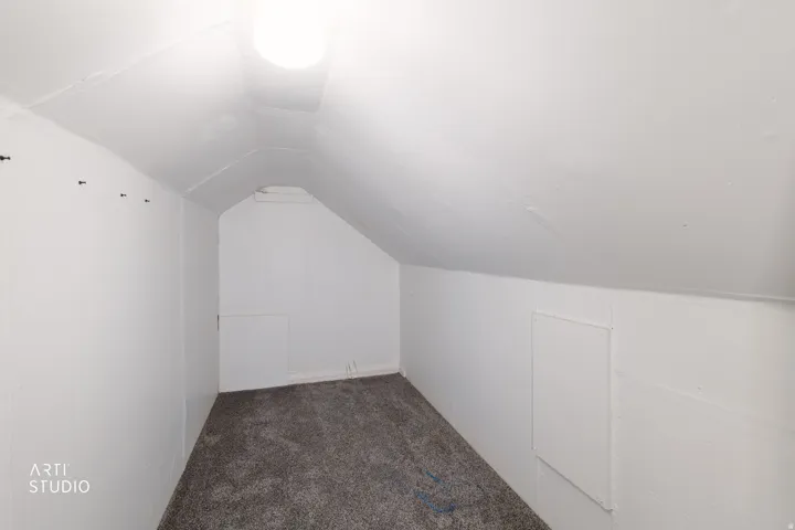 Carpeted flooring with sloped ceilings and a flush-mount ceiling light