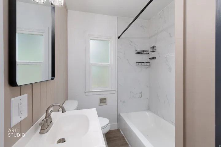 Full bathroom featuring a single vanity, a shower/tub combination with a tiled surround, and wood-finish flooring