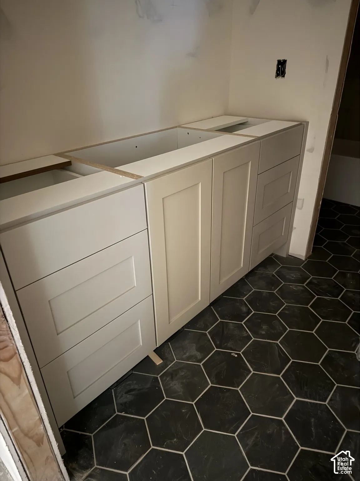 Shaker-style vanity cabinetry in a neutral finish paired with geometric hexagonal floor tiling