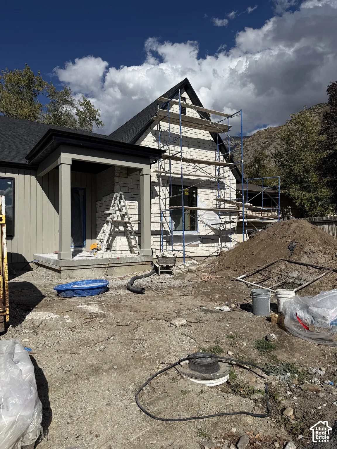 Exterior featuring vertical siding, stone masonry veneer, dark shingle roof, and a covered front porch
