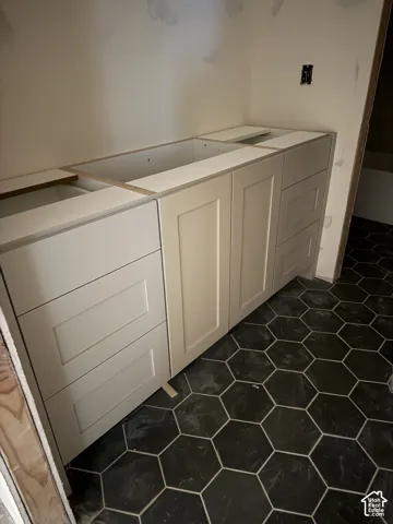 Shaker-style vanity cabinetry in a neutral finish paired with geometric hexagonal floor tiling