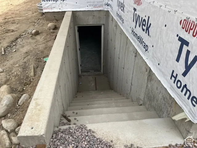 Concrete exterior stairs leading to an entry door, with a concrete retaining wall