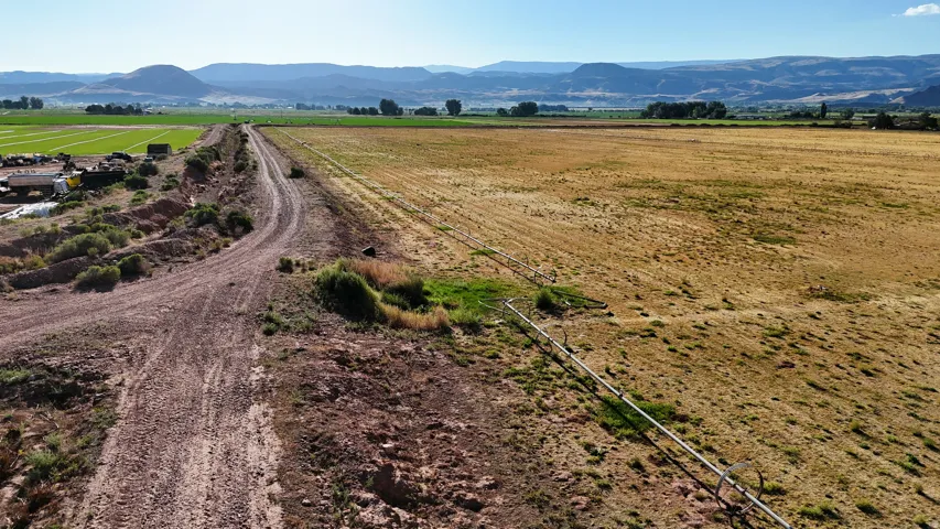 Expansive agricultural land featuring a natural terrain road and irrigation system