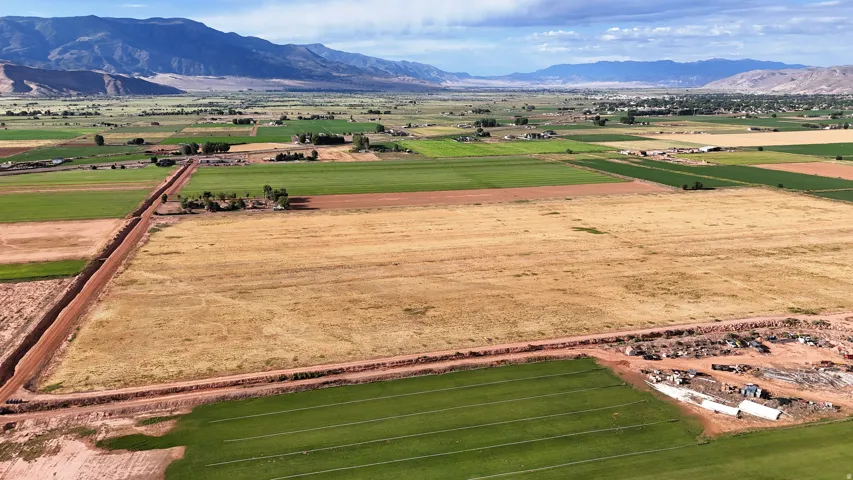 Expansive agricultural acreage featuring cultivated fields and undeveloped land with distant mountains