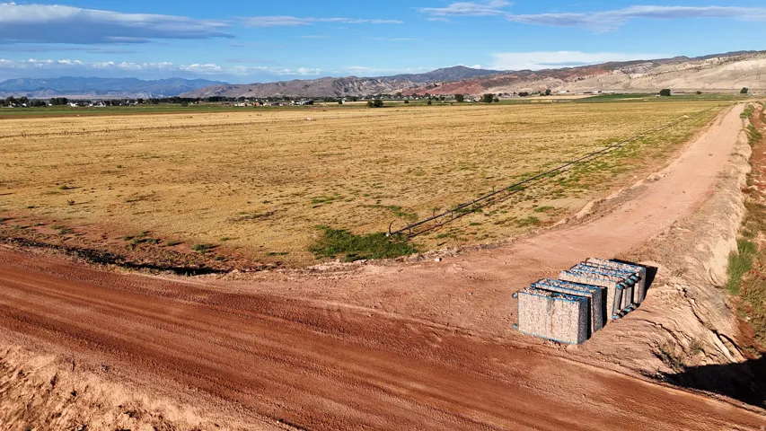 Expansive land parcel with a dirt road, rural setting, and distant mountainous terrain