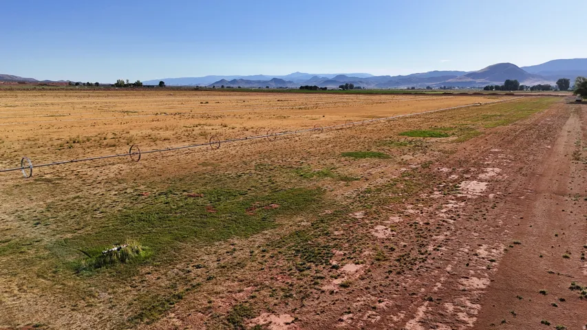 Expansive rural landscape featuring a clear sky, distant mountains, and an irrigation system