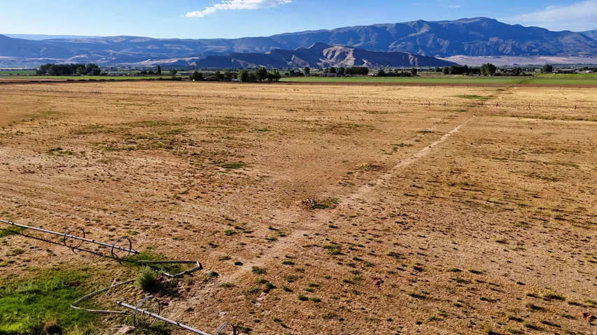 Expansive open terrain with visible irrigation system, framed by distant mountains and a clear sky