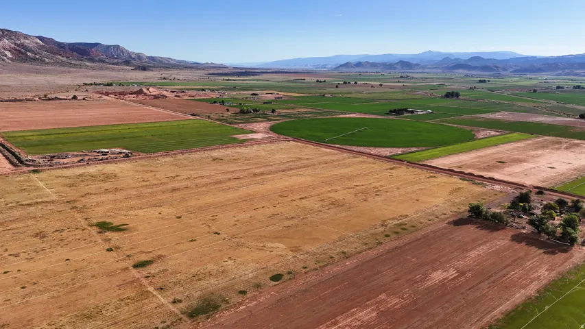 Expansive agricultural land featuring cultivated fields, natural terrain, and distant mountain ranges