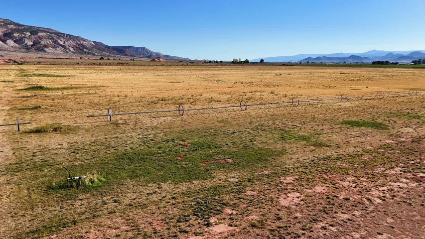Expansive open land featuring diverse topography, distant mountain ranges, and visible irrigation equipment