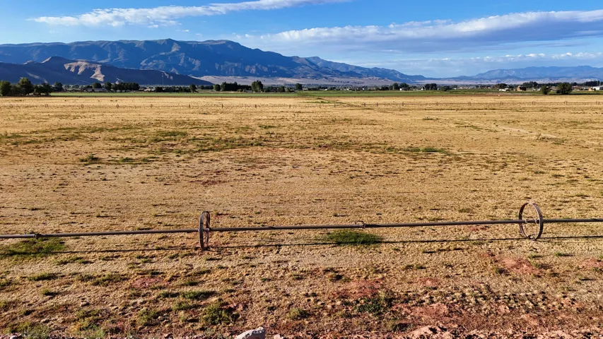 Expansive open land featuring distant mountain ranges and a visible irrigation system