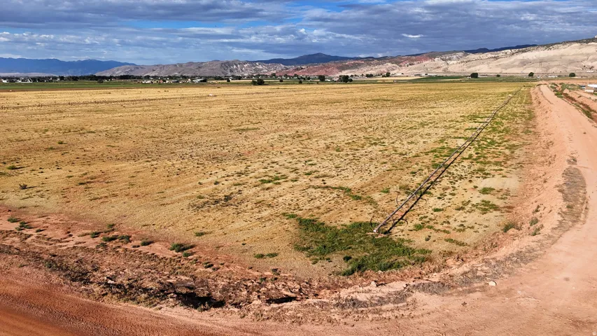 Expansive open land with a dirt road access, distant mountain range, and scattered vegetation