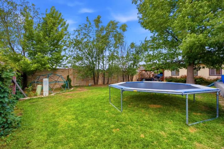 Expansive grassy yard featuring mature trees and a stone privacy wall