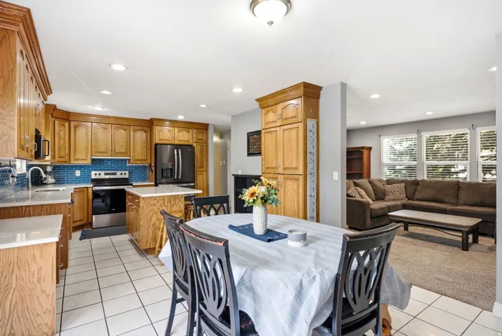 Kitchen with wood cabinetry, stainless steel appliances, a tiled backsplash, and recessed lighting
