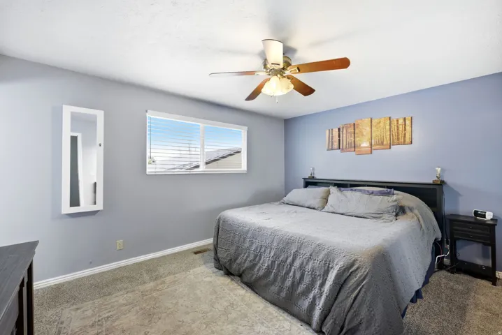 Bedroom featuring carpeted flooring, a window with blinds, and a ceiling fan with integrated lighting