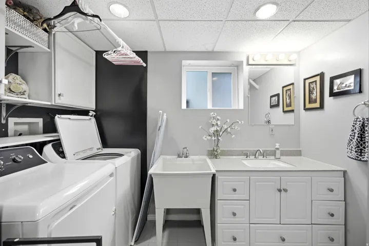 Laundry area featuring a utility sink, white cabinetry, integrated shelving, and a vanity with a countertop and sink