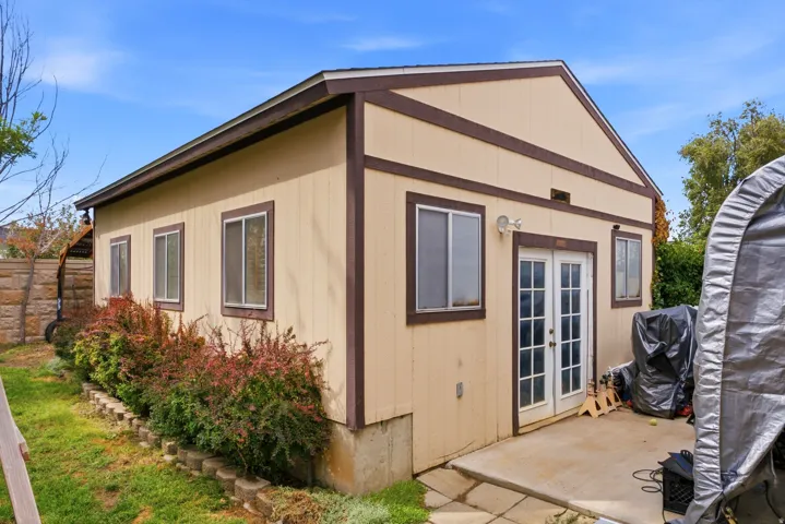 Detached accessory structure featuring multiple windows, a concrete patio, and a double French door entry