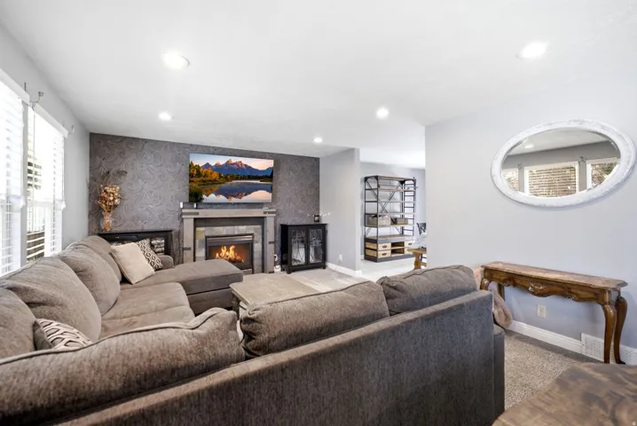 Recessed lighting, window with blinds, textured accent wall, fireplace with stone surround, and built-in shelving
