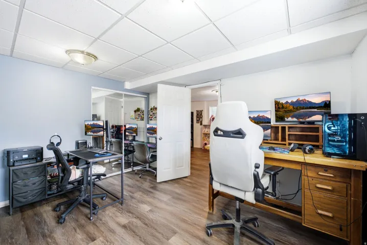 Spacious room featuring wood-finish flooring, a drop ceiling with recessed lighting, and light blue wall paint