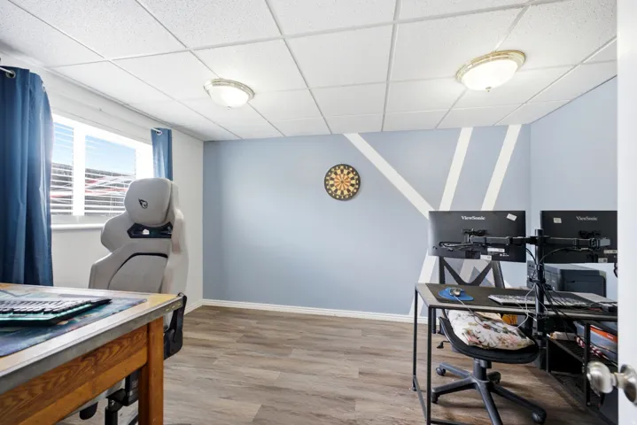 Wood-finish flooring, drop ceiling with integrated lighting, window with blinds, decorative wall treatment