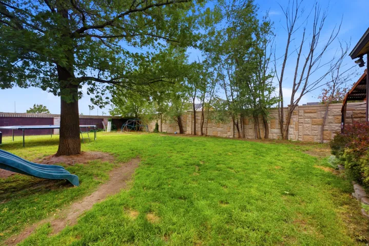 Expansive lawn area with mature trees and stone perimeter wall
