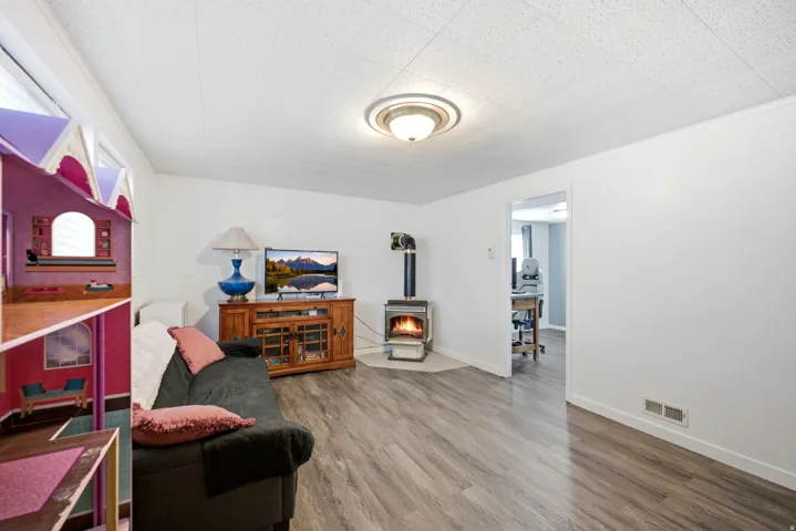 Wood-finish flooring throughout, white walls, and a freestanding wood-burning stove with hearth
