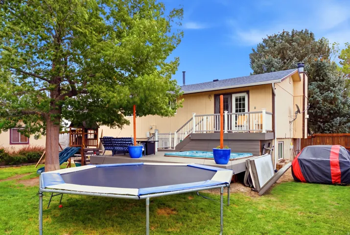 Expansive green lawn with mature trees and a multi-level wood deck