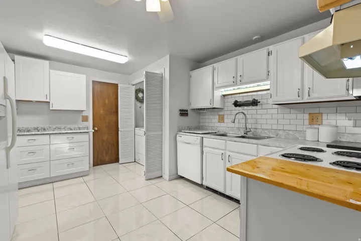 Kitchen featuring white cabinetry, light-toned countertops, subway tile backsplash, and tile flooring