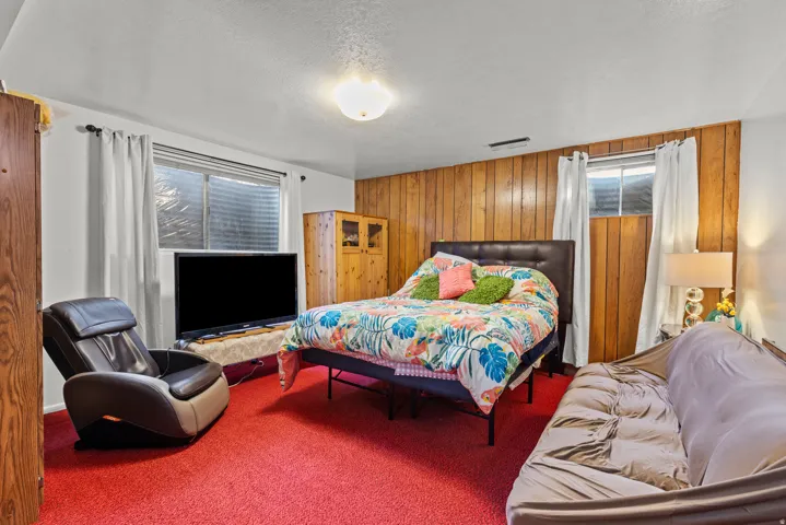 Wall paneling, red carpeting, window with blinds, and white painted walls