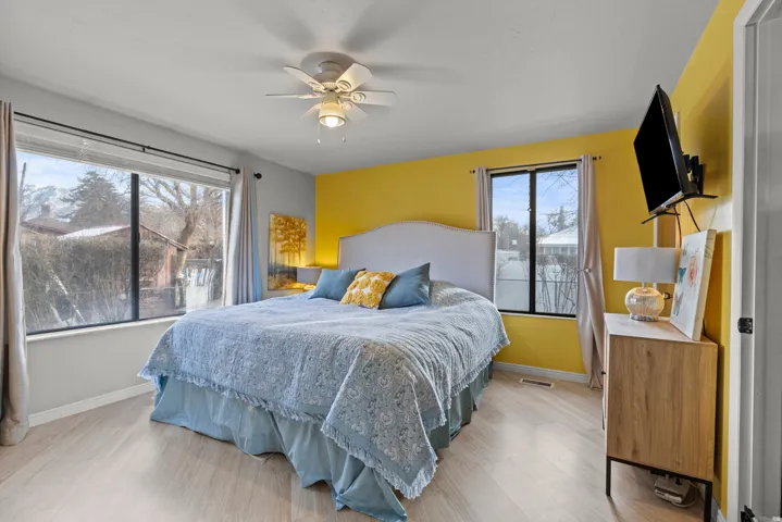 Wood-finish flooring, ceiling fan with integrated lighting, and multiple windows