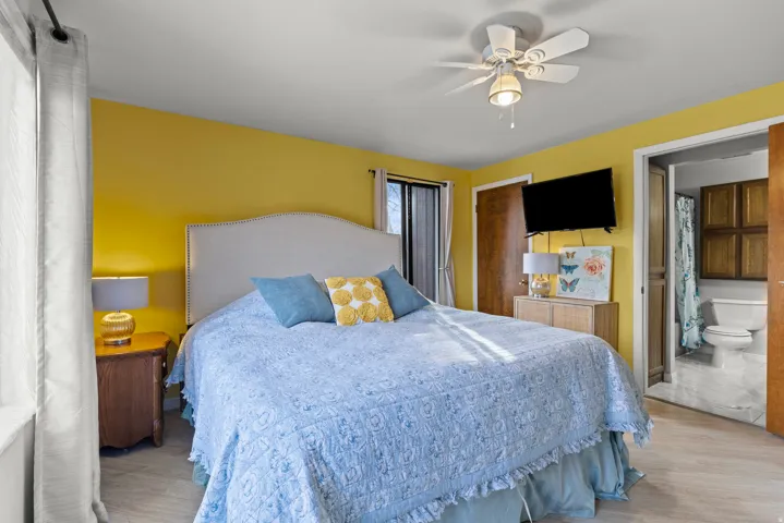 Ceiling fan, wood-finish flooring, attached lighting, and a bathroom with tile flooring