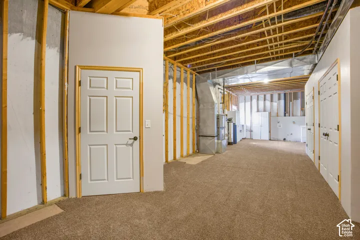 Unfinished lower level with exposed ceiling joists, framed walls, and carpeting