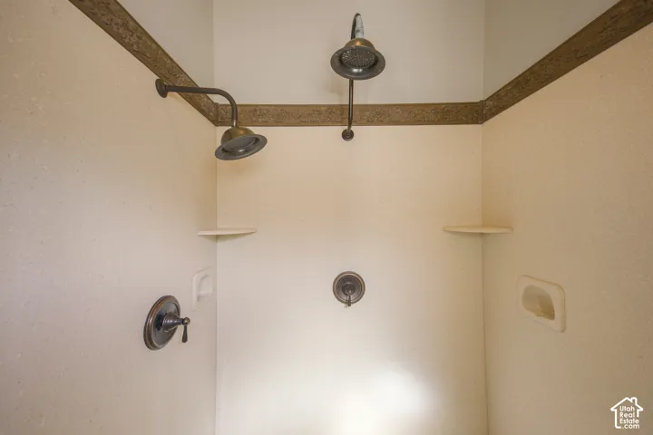 Dual shower heads with dark bronze fixtures, integrated corner shelving, and a built-in soap dish