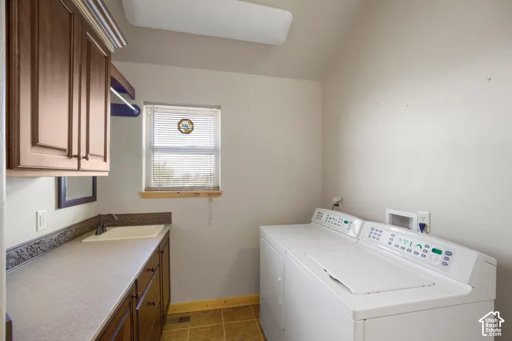 Laundry area featuring upper cabinetry, a sink with countertop, and tile flooring
