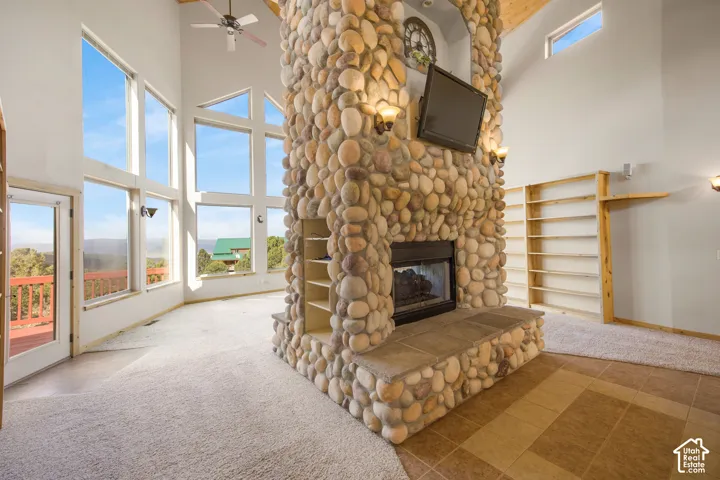 Floor-to-ceiling windows, river rock fireplace with hearth, vaulted ceiling, built-in shelving, mixed flooring