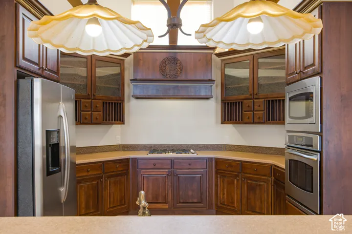 Kitchen featuring wood cabinetry, stainless steel refrigerator, built-in stainless steel oven and microwave, and a gas cooktop